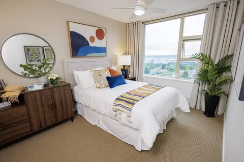 Bedroom with a large bed, patterned throw, abstract art and broad windows