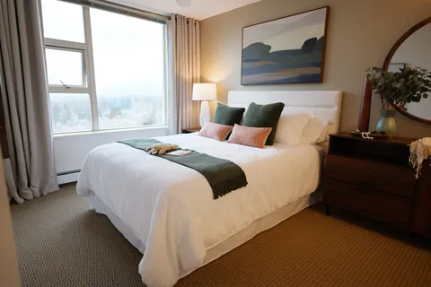 Bedroom with a bed, green throw, landscape art and a window