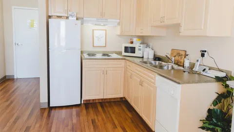 Kitchenette with white cabinets, refrigerator and microwave.