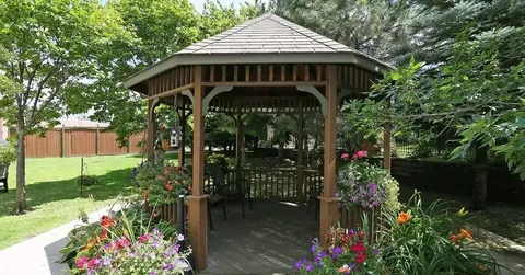 Wooden gazebo surrounded by flowers and trees