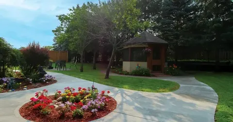 Garden path around a circular flower bed with a gazebo and trees