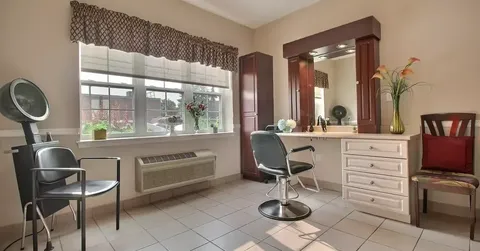 Salon chair, hair dryer and mirrors beside a window