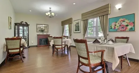 Dining tables with white tablecloths beside windows and floral artwork