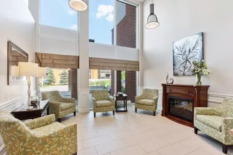 Tall-window seating area with green armchairs and a fireplace