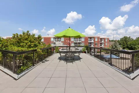 Roof terrace with a green umbrella, chairs and tables