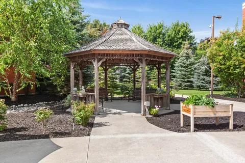 Wooden gazebo beside a planted garden and raised planting bed