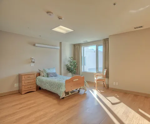 Bedroom with a bed, chest of drawers and a chair beside a window