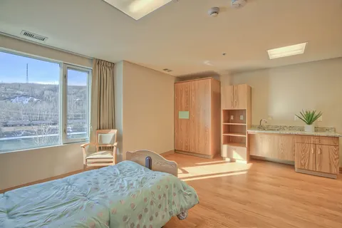 Bedroom with a bed, wooden wardrobe and kitchenette
