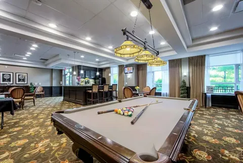 Room with a pool table and seating beside large windows