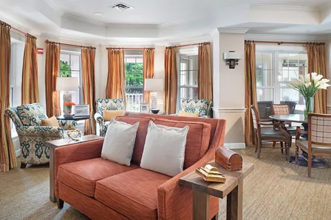 Sitting room with a sofa, patterned armchairs and large windows.