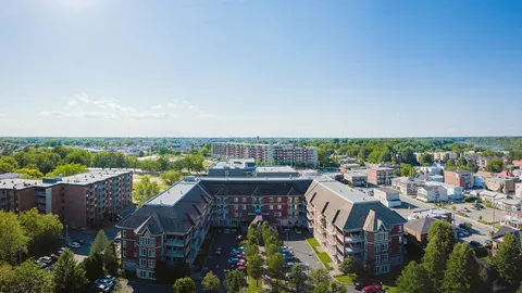Wide aerial view of a brick building, its courtyard and the surrounding neighbourhood
