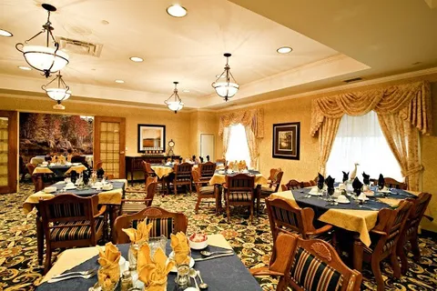 Dining room with set tables, wooden chairs, pendant lights and patterned carpet