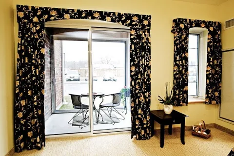 Sliding glass door and floral curtains beside a balcony with a round table and chairs