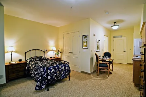Room with a bed, bedside cabinets, lamps, kitchenette and a small dining table