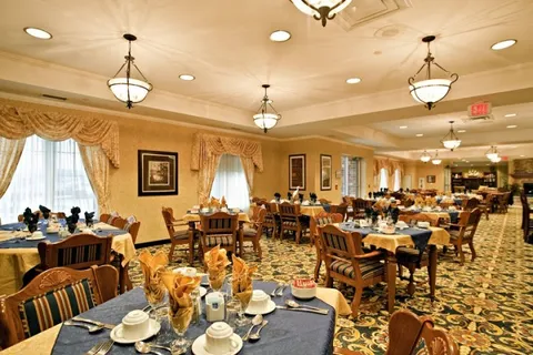 Dining room with set tables, upholstered wooden chairs, pendant lights and curtained windows