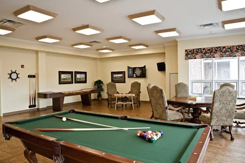 Games room with a pool table, shuffleboard table, dartboard and upholstered chairs