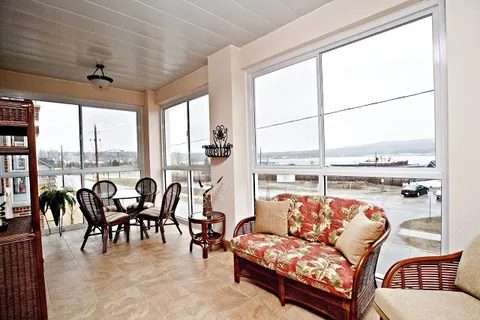 Sunroom with wicker seating, a round table, large windows and a view of the water