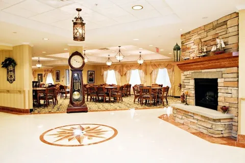 Stone fireplace and grandfather clock beside a tiled floor and a dining room