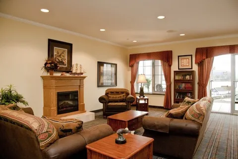 Room with sofas, an armchair, a fireplace, bookcase and model ships