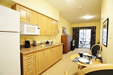 Kitchenette with wooden cabinets, a fridge, microwave and round dining table