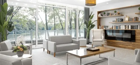 Sitting area with pale chairs, a sofa, bookshelves and a chessboard