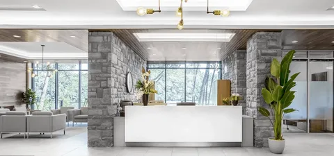 Reception desk framed by stone columns and large windows