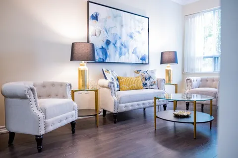 Sitting area with a cream sofa, two armchairs and blue abstract artwork
