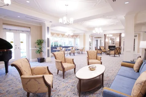 Lounge with cream armchairs, a blue sofa, chandeliers and a piano