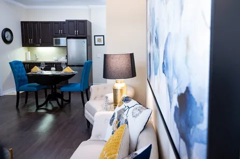 Suite with a sofa, dining table, blue chairs and kitchen cabinets
