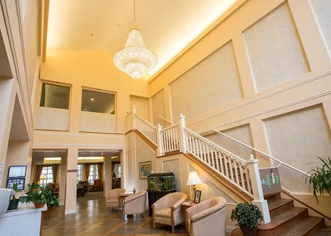 Entrance lobby with a broad staircase, seating and chandelier.