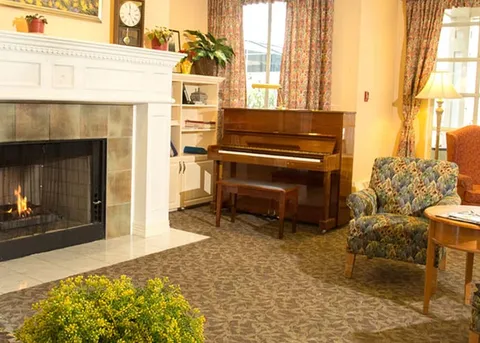 Lounge with a fireplace, piano and armchair.