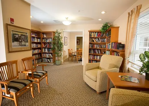 Library lounge with bookshelves, chairs and large windows.