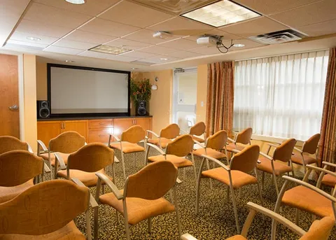 Screening room with rows of upholstered chairs and a projection screen.
