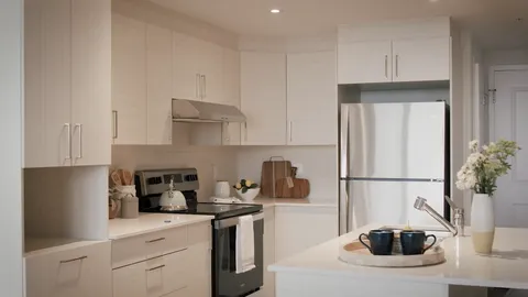 Suite kitchen with white cabinets, a stove and refrigerator.