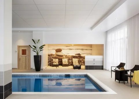 Indoor pool with surrounding seating and large windows.