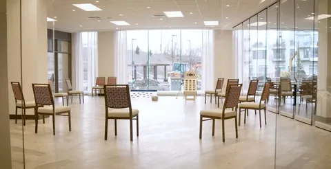 Activity room with tables, chairs and large windows.