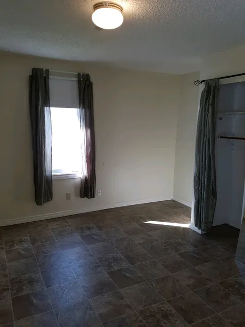 Empty room with a window, curtains and a tiled floor