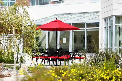Patio with black metal chairs and tables beneath a red umbrella