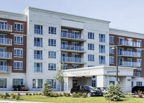 Residence entrance with balconies, parked cars and landscaped shrubs