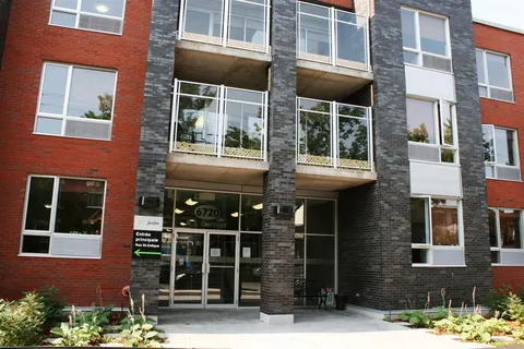 Brick and stone residence facade with balconies and glass entrance.