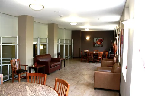 Lounge with sofas, tables and windows beside a dining area.