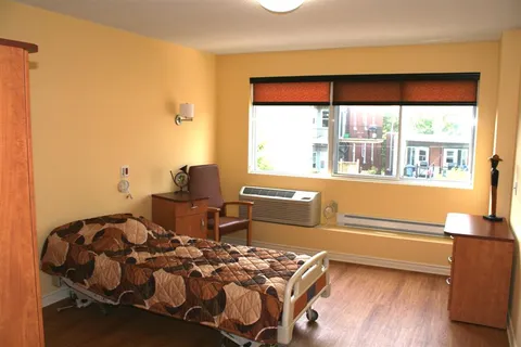 Bedroom with adjustable bed, bedside cabinet and large window.