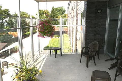 Covered balcony with outdoor chairs and hanging flowers.