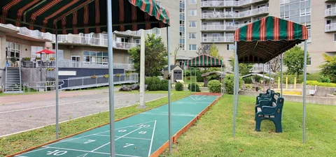 Outdoor shuffleboard court with striped shelters and a row of chairs