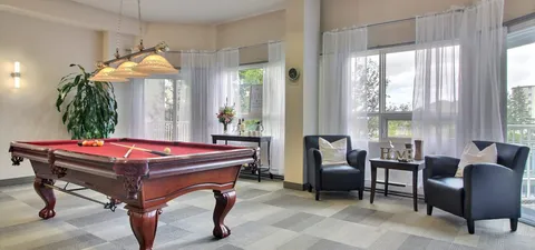 Billiards room with a red pool table and two dark armchairs