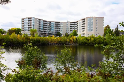 Multi-storey residence with balconies overlooking a river and trees