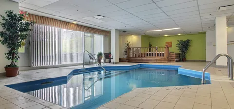 Indoor swimming pool with handrails and a raised wooden spa enclosure