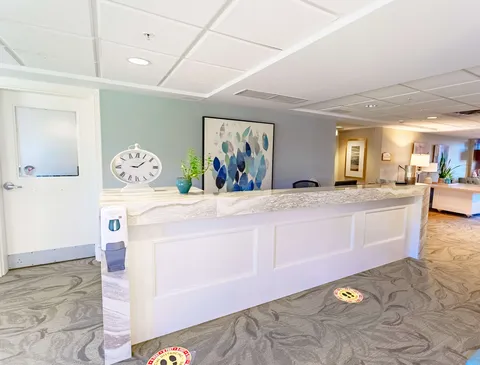 Reception counter with a large clock, plant and abstract wall art