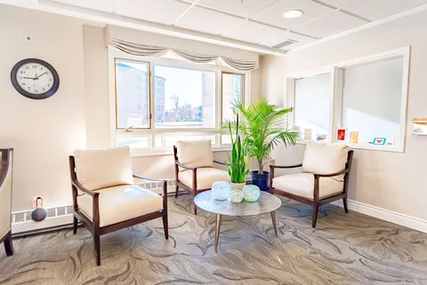 Armchairs around a round table beside a window and potted palm