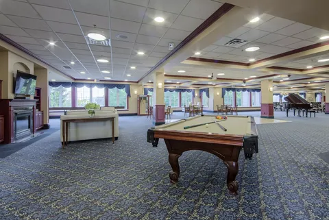 Billiards table in a large room with seating and a grand piano